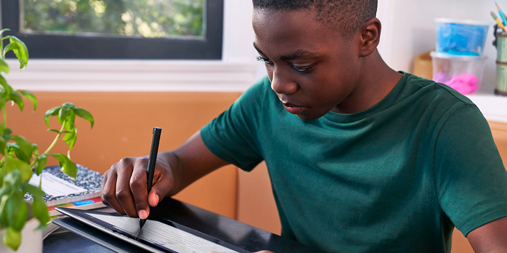 Estudante negro usando dispositivo Microsoft na aula